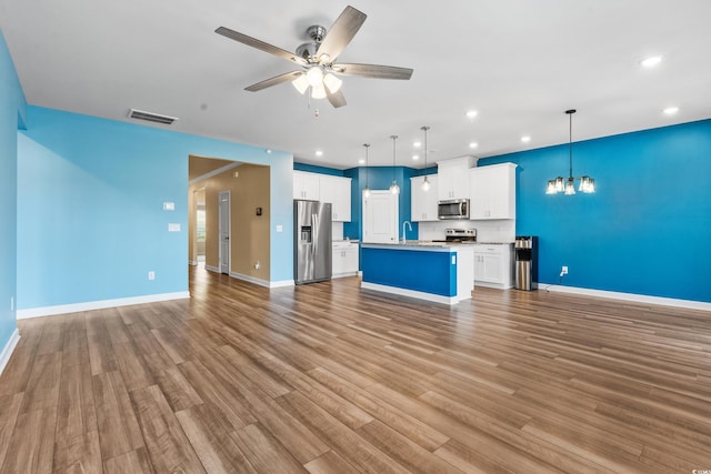 kitchen featuring ceiling fan with notable chandelier, white cabinetry, hanging light fixtures, a center island, and stainless steel appliances