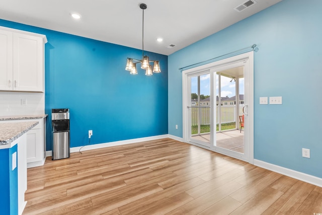 unfurnished dining area featuring a chandelier and light wood-type flooring