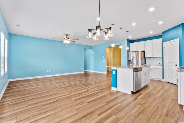 kitchen with white cabinetry, hanging light fixtures, stainless steel appliances, and an island with sink