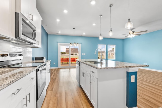 kitchen featuring sink, white cabinetry, light hardwood / wood-style flooring, appliances with stainless steel finishes, and a kitchen island with sink