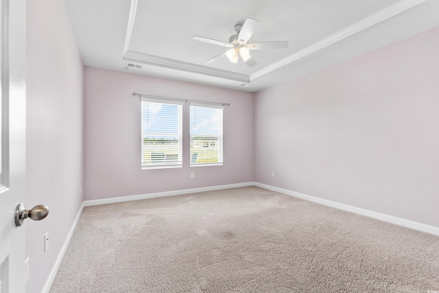 carpeted empty room featuring a raised ceiling, crown molding, and ceiling fan