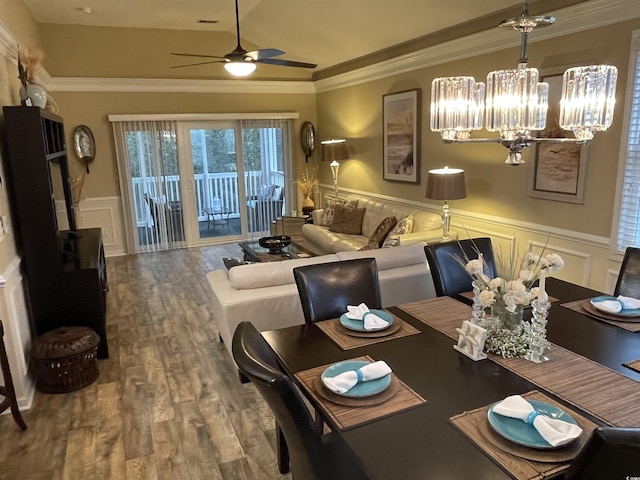 dining room with lofted ceiling, ornamental molding, ceiling fan with notable chandelier, and wood-type flooring