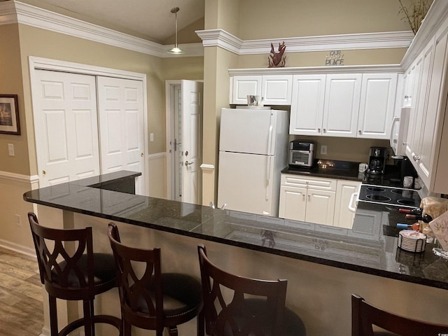 kitchen with a kitchen breakfast bar, white cabinets, white appliances, and kitchen peninsula