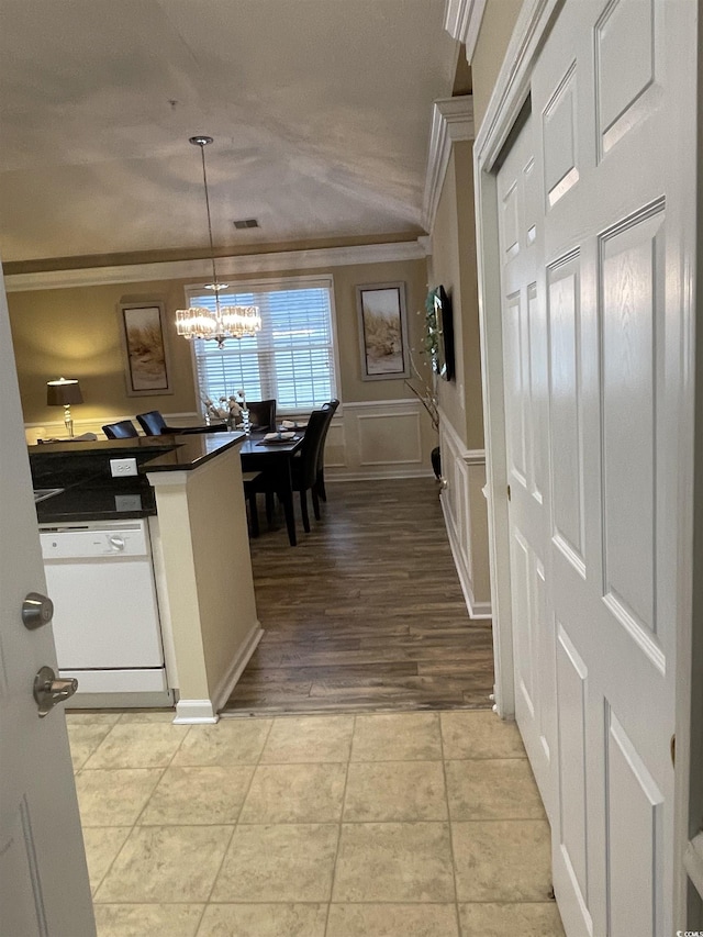 kitchen featuring pendant lighting, light tile patterned floors, crown molding, white dishwasher, and a chandelier