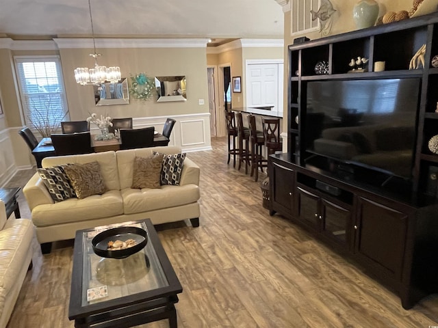 living room with a notable chandelier, wood-type flooring, and ornamental molding