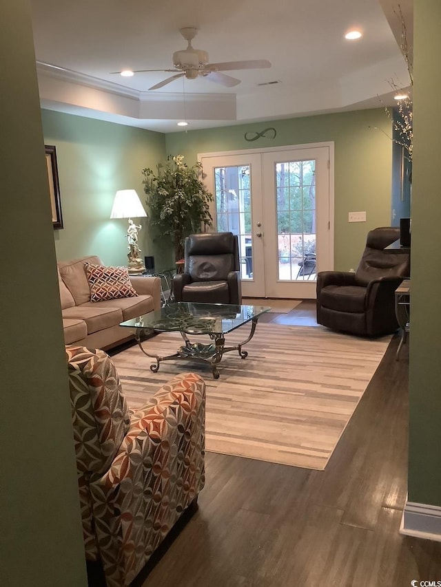 living room featuring french doors, ceiling fan, wood-type flooring, and a raised ceiling