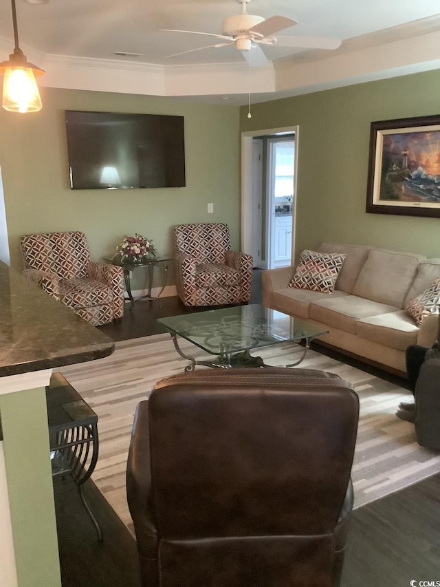 living room featuring hardwood / wood-style floors, crown molding, and ceiling fan