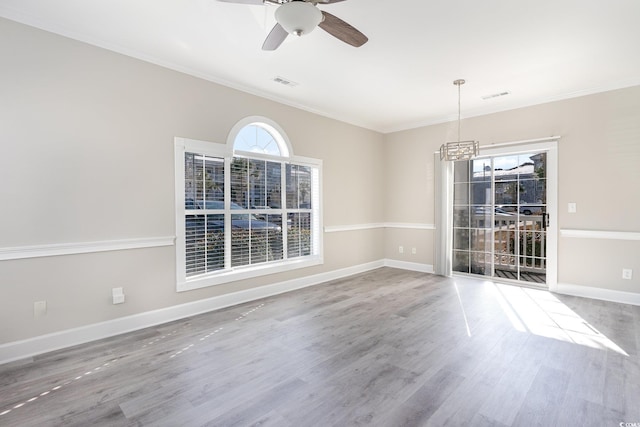 unfurnished dining area featuring ornamental molding, ceiling fan with notable chandelier, and hardwood / wood-style floors