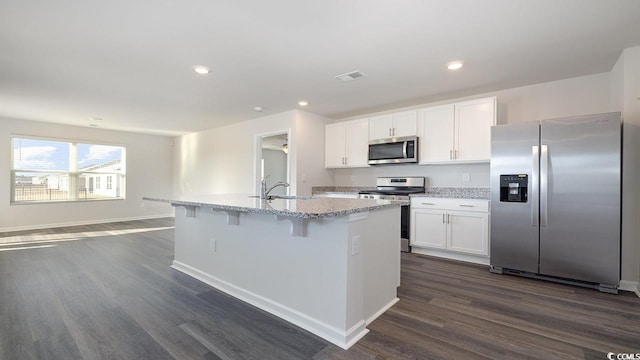 kitchen with stainless steel appliances, an island with sink, dark hardwood / wood-style floors, and white cabinets