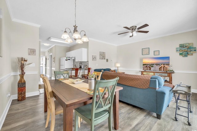 dining space with crown molding, ceiling fan with notable chandelier, and light hardwood / wood-style flooring