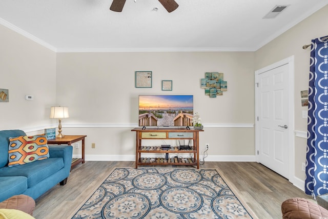 living room with wood-type flooring, ornamental molding, and ceiling fan