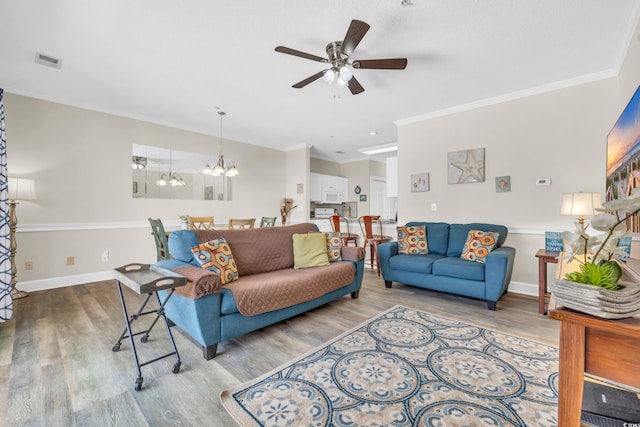 living room featuring crown molding, hardwood / wood-style flooring, and ceiling fan with notable chandelier