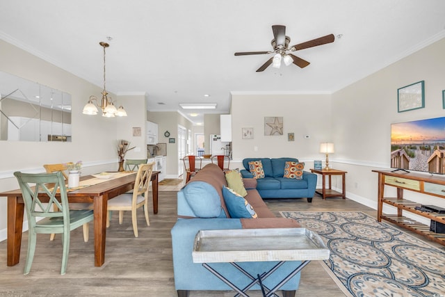 living room featuring hardwood / wood-style flooring, ceiling fan with notable chandelier, and ornamental molding