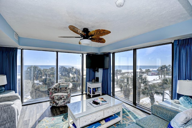 living room featuring ceiling fan, wood-type flooring, a textured ceiling, and a wealth of natural light