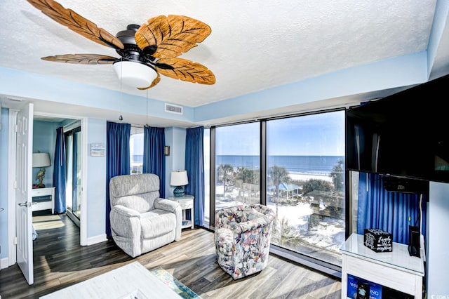 living room featuring ceiling fan, hardwood / wood-style floors, a textured ceiling, and baseboard heating