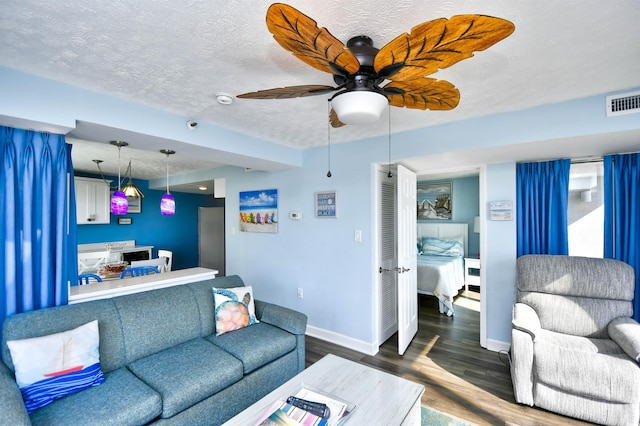 living room featuring ceiling fan, dark hardwood / wood-style floors, and a textured ceiling