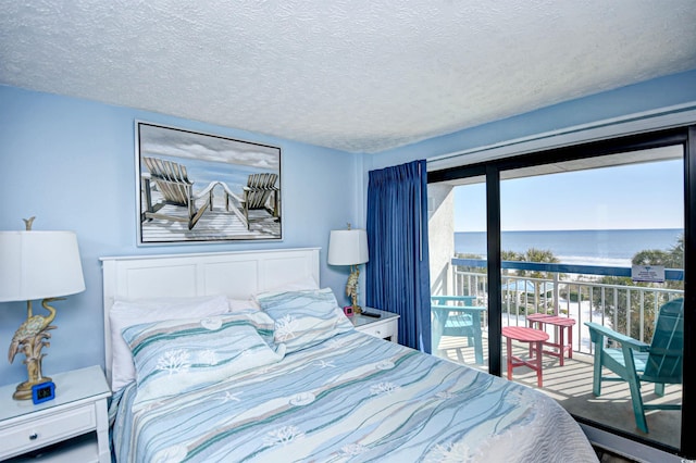 bedroom featuring access to outside, a textured ceiling, and a water view