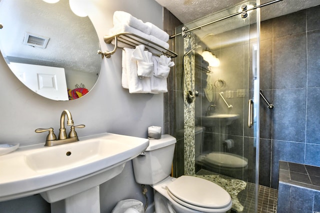 bathroom featuring toilet, sink, a textured ceiling, and walk in shower