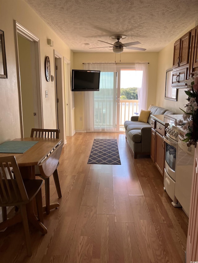 interior space featuring ceiling fan, light hardwood / wood-style flooring, gas stove, and a textured ceiling