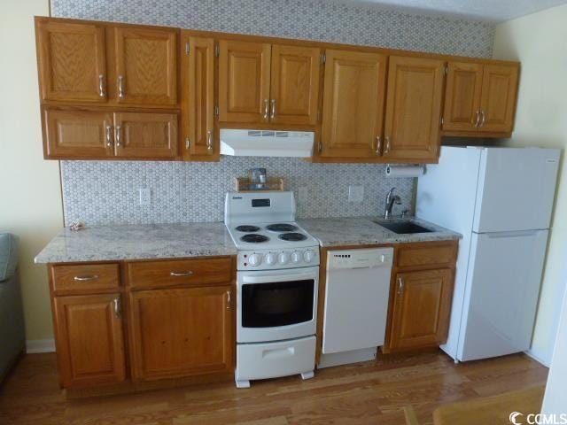 2710 Ocean Blvd S Unit 406, Myrtle Beach, SC 29577 - kitchen with white appliances, ventilation hood, light wood-style floors, backsplash, and brown cabinets