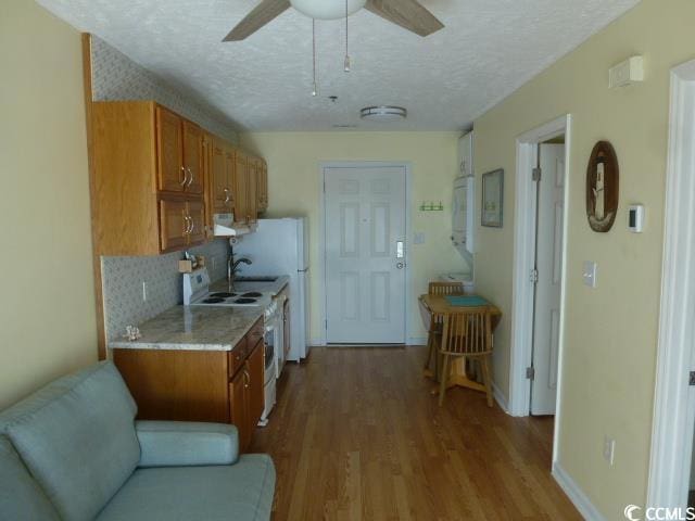 kitchen featuring a textured ceiling, ceiling fan, light hardwood / wood-style floors, decorative backsplash, and white range with electric stovetop