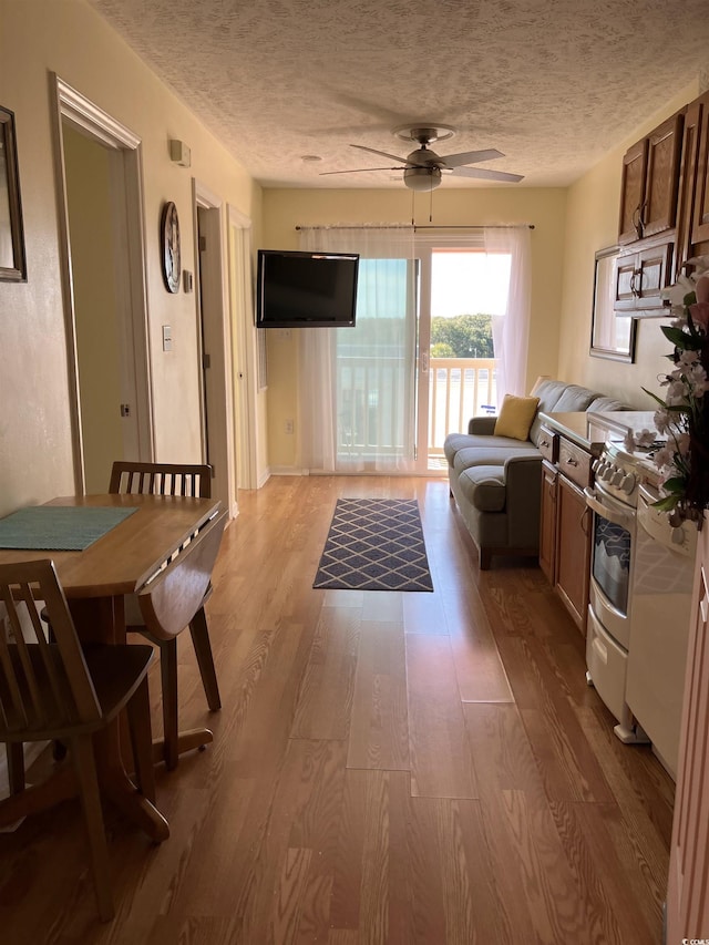 2710 Ocean Blvd S Unit 406, Myrtle Beach, SC 29577 - kitchen with wood finished floors, a ceiling fan, stove, a textured ceiling, and stainless steel microwave