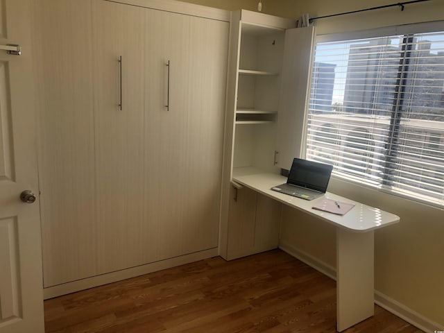 unfurnished office featuring dark wood-type flooring and a healthy amount of sunlight