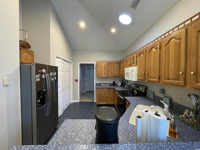 kitchen featuring stainless steel appliances, lofted ceiling, sink, and dark tile patterned flooring