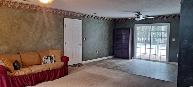 unfurnished living room with a ceiling fan, baseboards, a textured ceiling, and carpet flooring