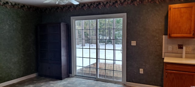 doorway to outside with ceiling fan and baseboards