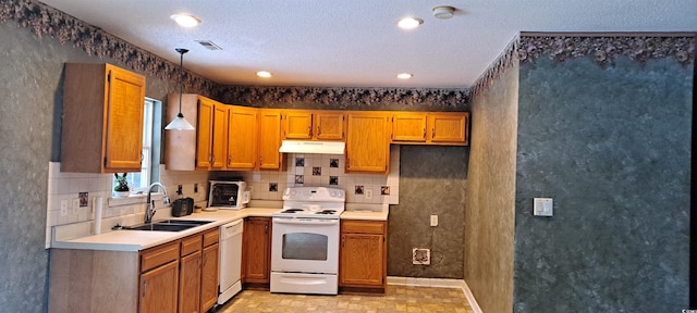 kitchen featuring pendant lighting, light countertops, a sink, white appliances, and under cabinet range hood