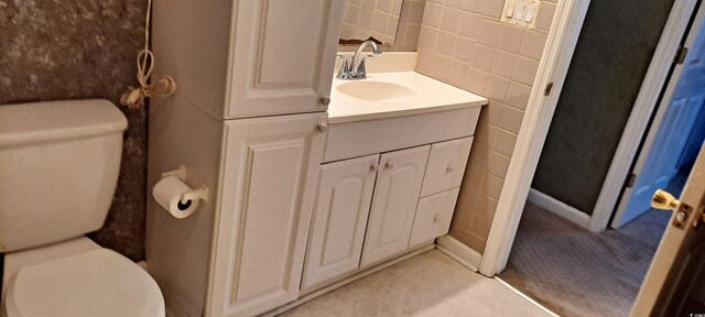 bathroom featuring toilet, tile walls, and vanity