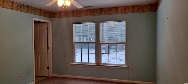 spare room featuring baseboards, visible vents, ceiling fan, carpet, and a textured ceiling