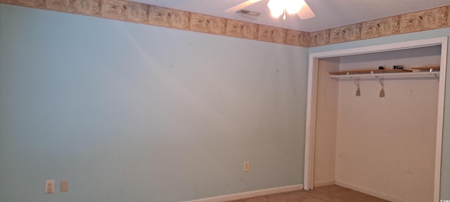 interior space with ceiling fan, light carpet, and a closet