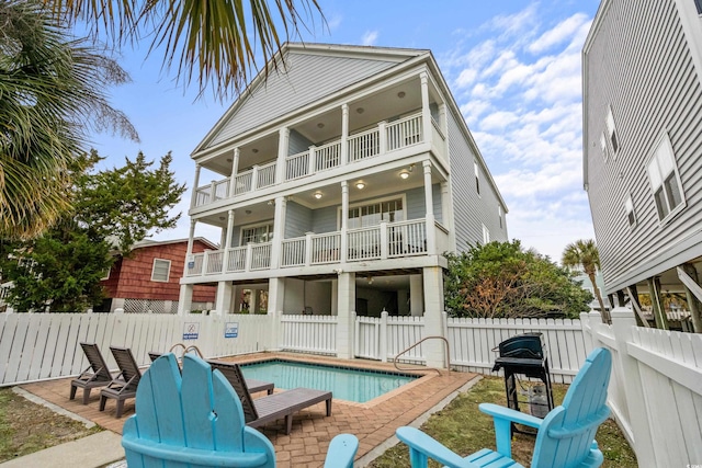 back of house featuring a fenced in pool, a patio, and a balcony