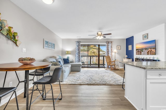 dining area featuring baseboards, light wood finished floors, and ceiling fan