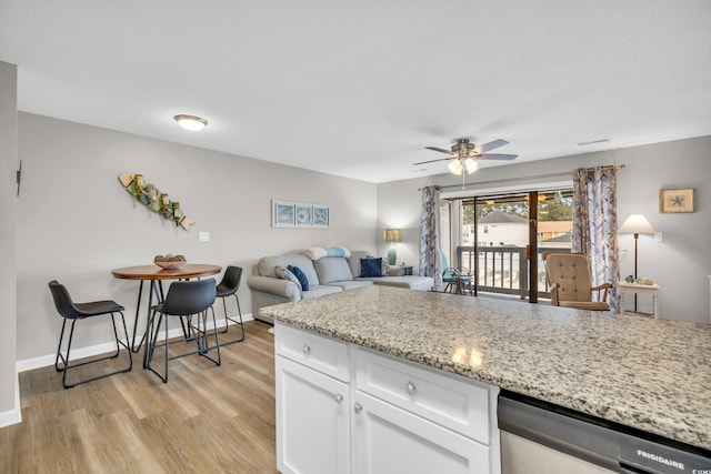 kitchen featuring light stone counters, light wood-style floors, white cabinets, baseboards, and dishwasher