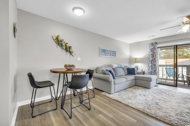 living area featuring a ceiling fan, baseboards, and wood finished floors