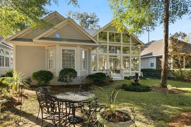 rear view of house with a sunroom and a lawn