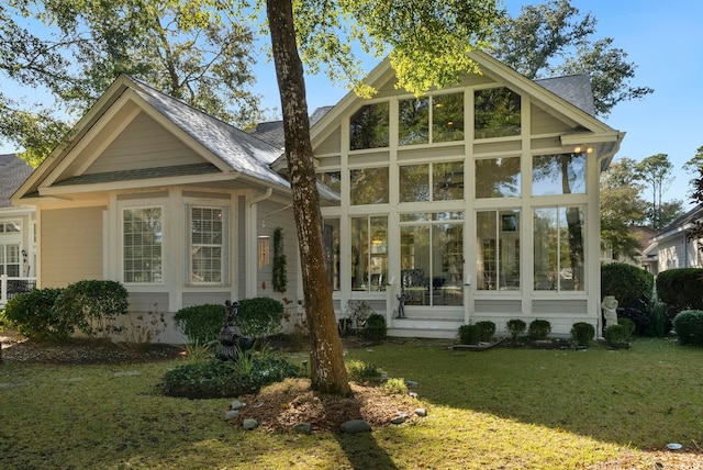 rear view of house with a sunroom and a yard