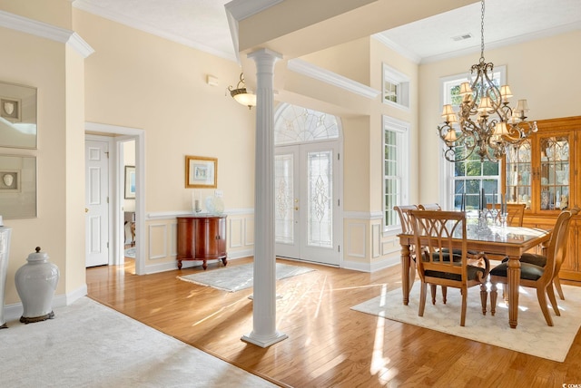 dining space featuring decorative columns, ornamental molding, plenty of natural light, and an inviting chandelier