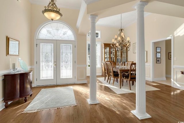 foyer featuring hardwood / wood-style floors, ornamental molding, decorative columns, and french doors