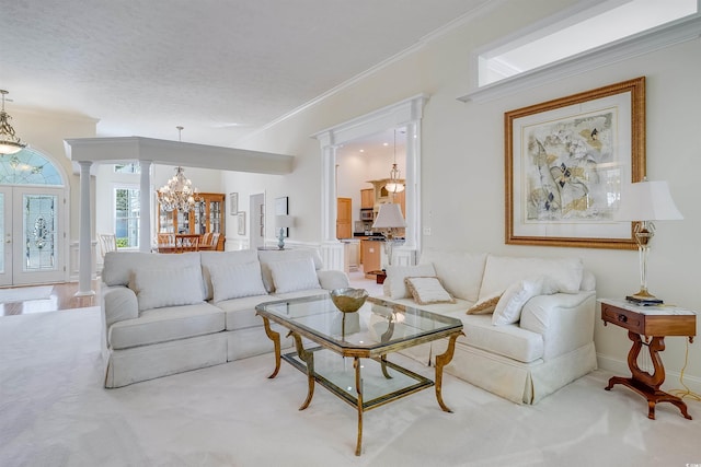 living room with a notable chandelier, ornamental molding, french doors, and ornate columns