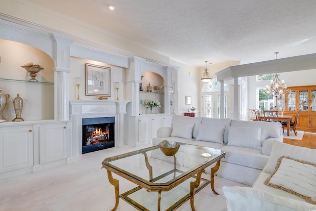 living room with crown molding, decorative columns, a textured ceiling, and a notable chandelier