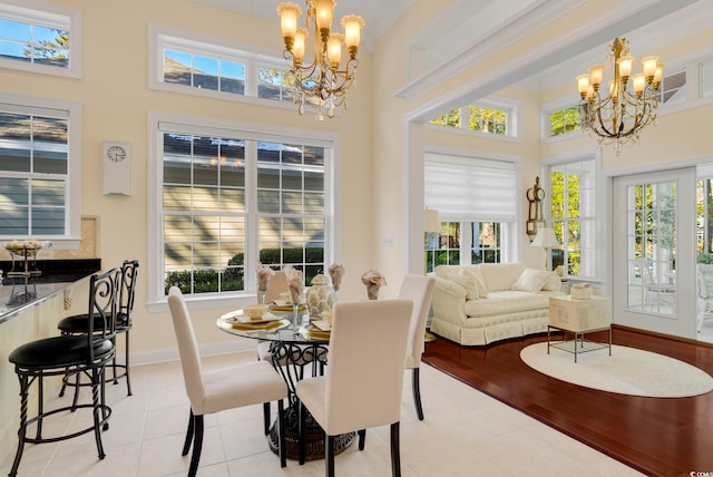 tiled dining space with an inviting chandelier, a healthy amount of sunlight, and a high ceiling