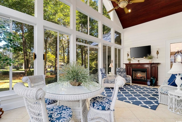 sunroom featuring lofted ceiling, wood ceiling, ceiling fan, plenty of natural light, and a fireplace