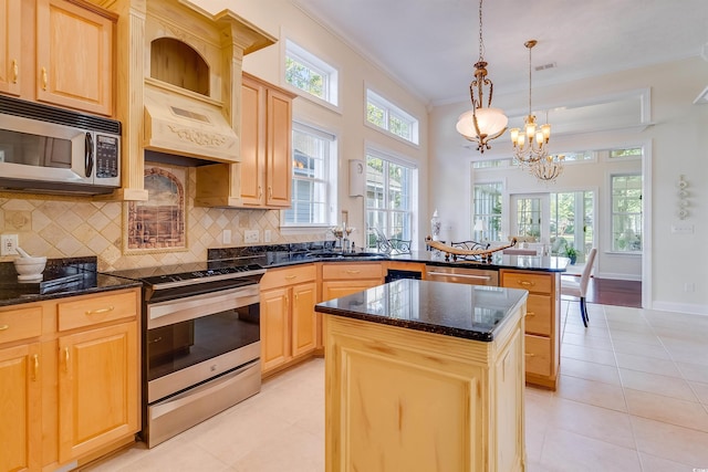 kitchen featuring decorative light fixtures, backsplash, a center island, stainless steel appliances, and light brown cabinets