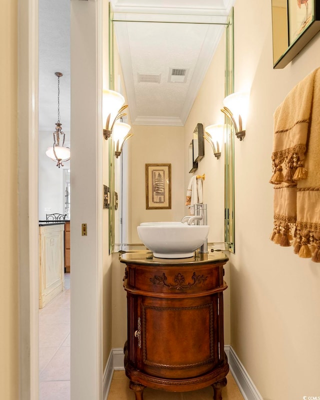 corridor featuring ornamental molding, sink, light tile patterned flooring, and a textured ceiling