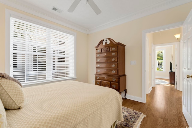 bedroom with wood-type flooring, ornamental molding, and ceiling fan