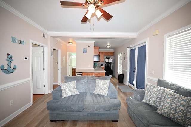 living room with crown molding, light hardwood / wood-style flooring, and ceiling fan